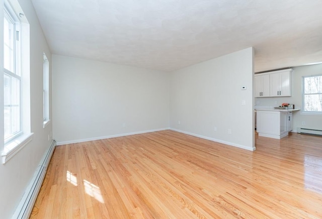 unfurnished living room featuring a baseboard radiator, baseboards, and light wood-style floors