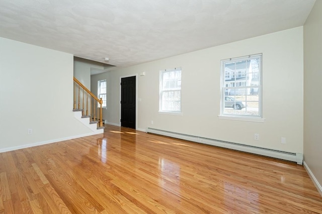 interior space with stairway, baseboards, a baseboard heating unit, and light wood-style floors