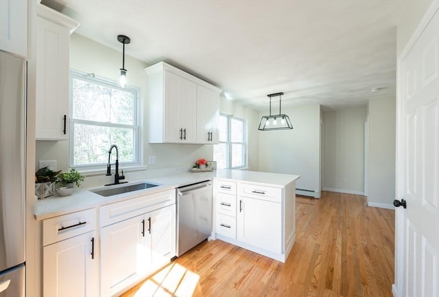 kitchen with light countertops, baseboard heating, appliances with stainless steel finishes, white cabinets, and a sink