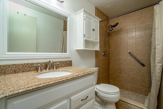 bathroom with toilet, vanity, and a tile shower