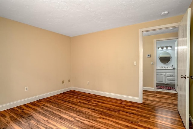 spare room featuring wood finished floors, a textured ceiling, baseboards, and a sink