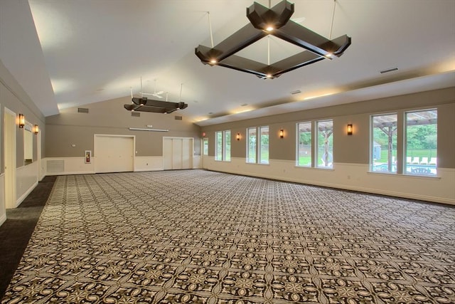 spare room featuring dark carpet, baseboards, visible vents, and high vaulted ceiling