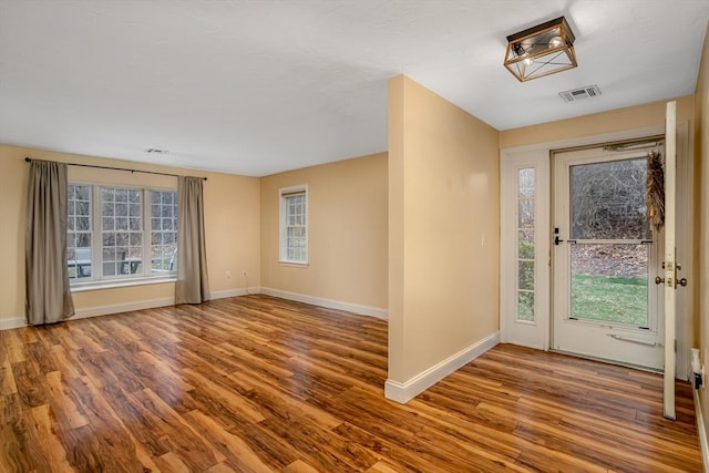foyer entrance with wood finished floors, visible vents, and a healthy amount of sunlight