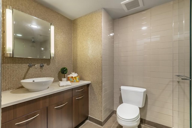 bathroom featuring toilet, vanity, tile patterned flooring, and a shower