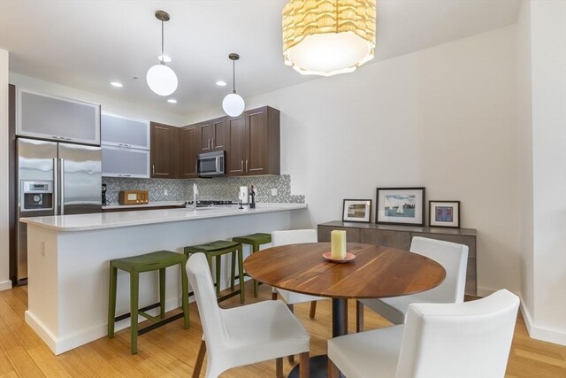 dining space with light wood-style flooring, recessed lighting, and baseboards