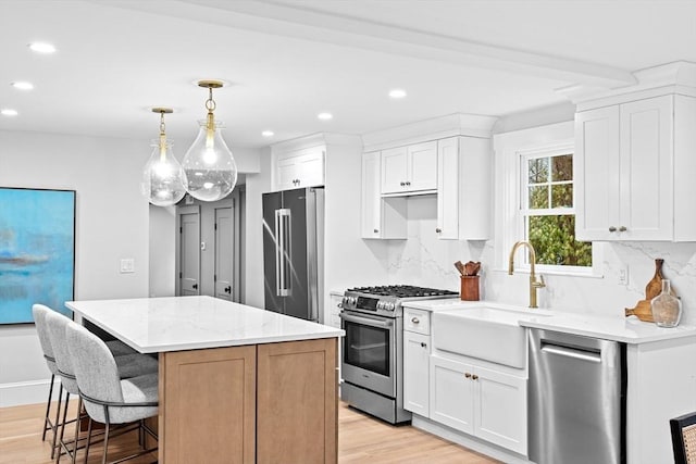 kitchen with a kitchen island, light stone counters, high quality appliances, white cabinets, and light wood-type flooring