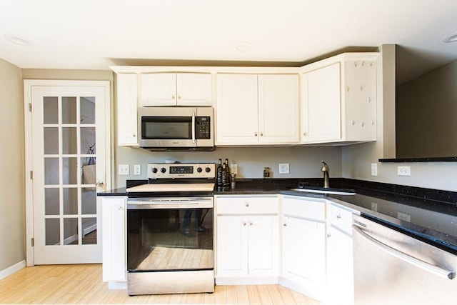 76 Kennedy Rd, West Brookfield, MA 01585 - kitchen featuring stainless steel appliances, a sink, light wood-style floors, white cabinetry, and dark stone counters