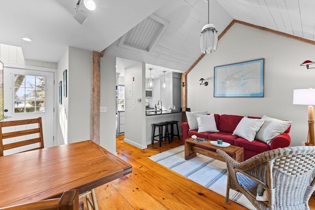 living room with light hardwood / wood-style floors, sink, and lofted ceiling