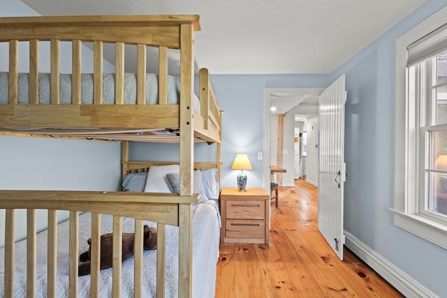 bedroom with light hardwood / wood-style flooring and a baseboard heating unit