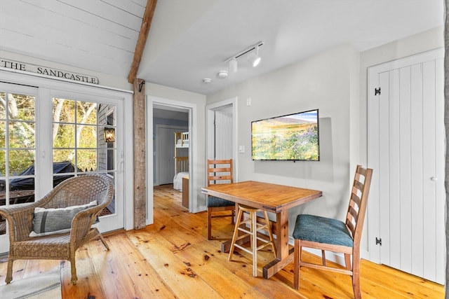 dining room with light hardwood / wood-style flooring and vaulted ceiling with beams