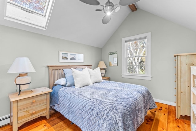 bedroom with a baseboard heating unit, hardwood / wood-style floors, ceiling fan, and lofted ceiling with skylight