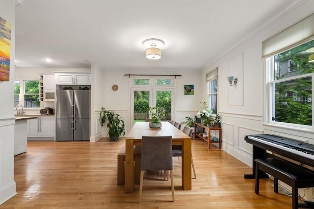 dining space featuring crown molding, light wood-style flooring, and a decorative wall