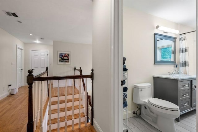 full bath featuring visible vents, toilet, vanity, wood finished floors, and baseboards