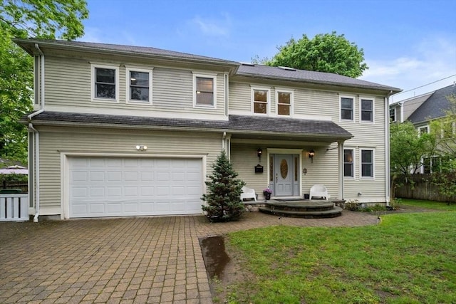 view of front of home with a front yard, decorative driveway, fence, and an attached garage