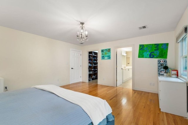 bedroom with visible vents, baseboards, connected bathroom, light wood-style flooring, and a chandelier