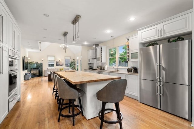 kitchen featuring wood counters, white cabinetry, stainless steel appliances, and open floor plan