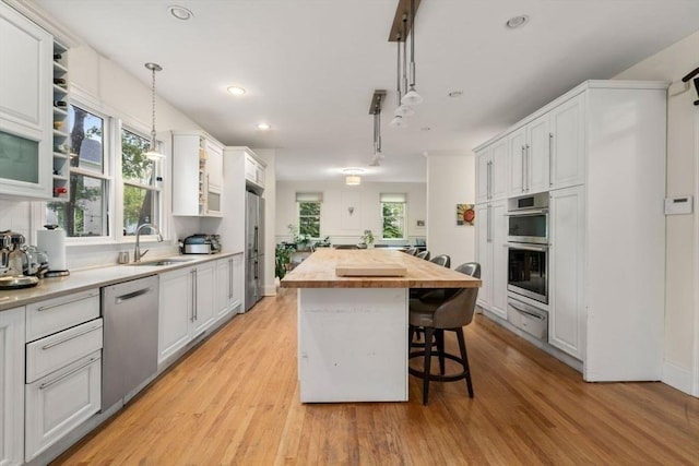 kitchen with a breakfast bar area, stainless steel appliances, a sink, a kitchen island, and wood counters