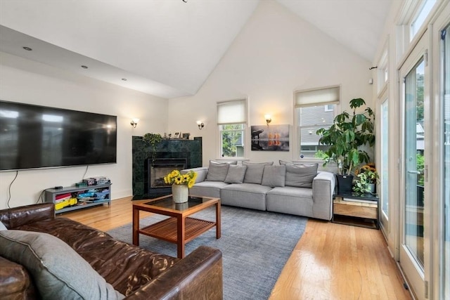 living area featuring high vaulted ceiling, wood finished floors, and a tile fireplace