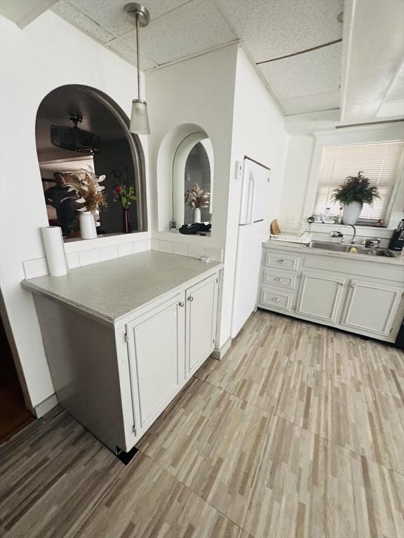 13 Coombs St, Southbridge, MA 01550 - kitchen featuring light wood-style floors, light countertops, a sink, white cabinetry, and a paneled ceiling