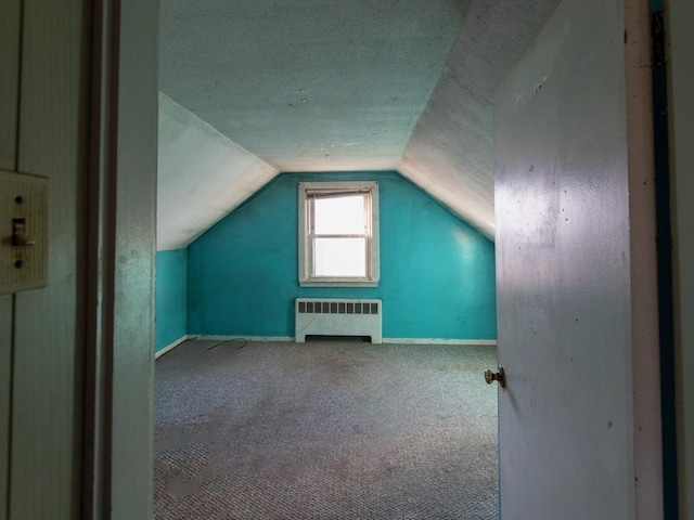 bonus room featuring radiator heating unit, carpet floors, a textured ceiling, and lofted ceiling