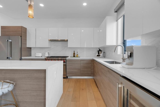 kitchen featuring sink, white cabinetry, premium appliances, decorative light fixtures, and beverage cooler