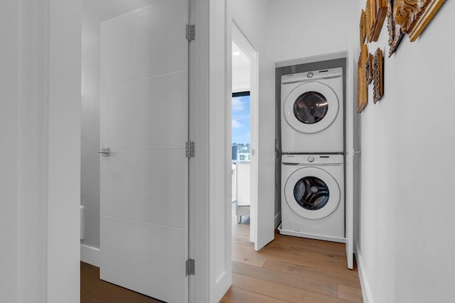 washroom with stacked washer and clothes dryer and wood-type flooring