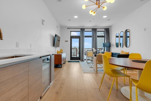 dining room with wine cooler, sink, light hardwood / wood-style flooring, and a notable chandelier