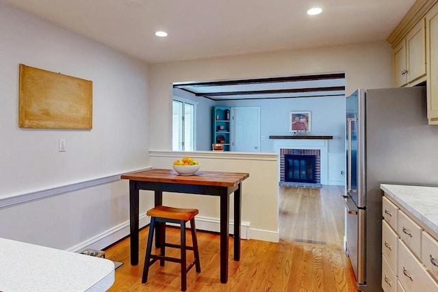 kitchen with light wood finished floors, a fireplace, recessed lighting, freestanding refrigerator, and light countertops