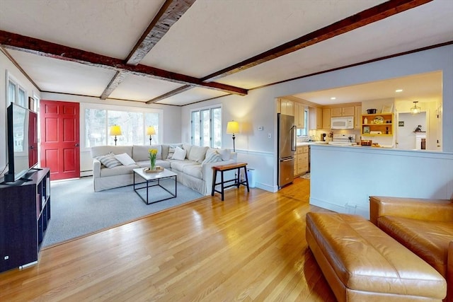 living room with beamed ceiling, light wood-style floors, and baseboard heating