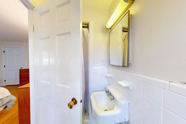 full bath with tile walls, wainscoting, and a sink