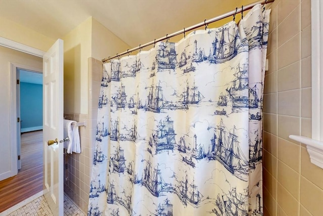 full bath with a shower with shower curtain, tile walls, and tile patterned floors