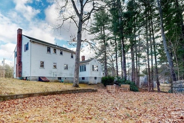 back of property with a chimney and fence