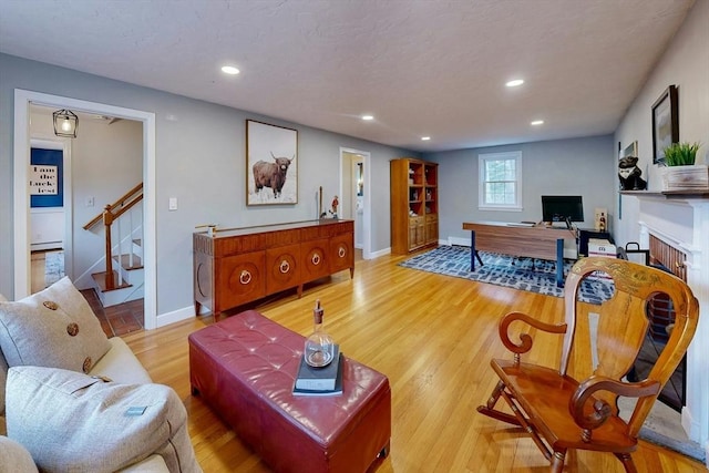 living area with light wood-style flooring, recessed lighting, stairway, a fireplace, and baseboards