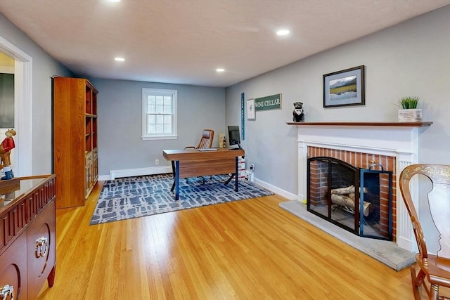 office featuring a brick fireplace, recessed lighting, light wood-style floors, and baseboards