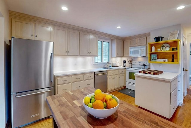 kitchen with light wood finished floors, light countertops, recessed lighting, stainless steel appliances, and a sink