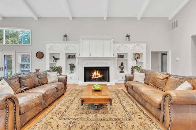 8 Fitch Farm Way, Southampton, MA 01073 - living room featuring beam ceiling, a warm lit fireplace, a high ceiling, and light wood-type flooring
