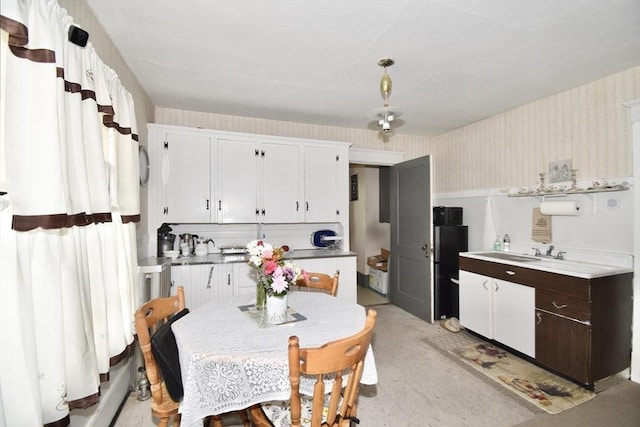 kitchen featuring wallpapered walls and white cabinetry