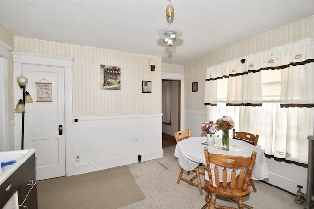 dining area featuring wallpapered walls and wainscoting
