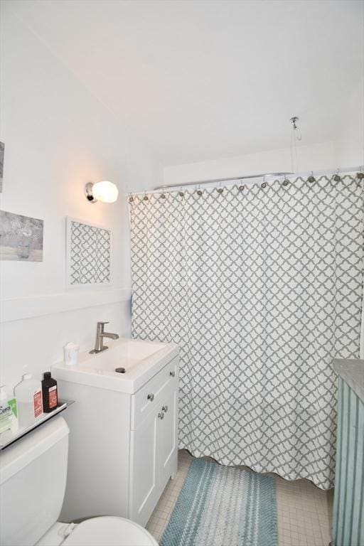 bathroom featuring toilet, vanity, tile patterned floors, and a shower with curtain