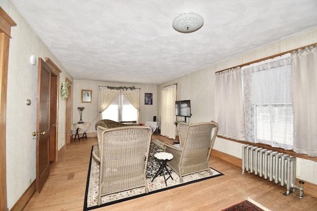 living area with radiator, light wood-type flooring, and baseboards