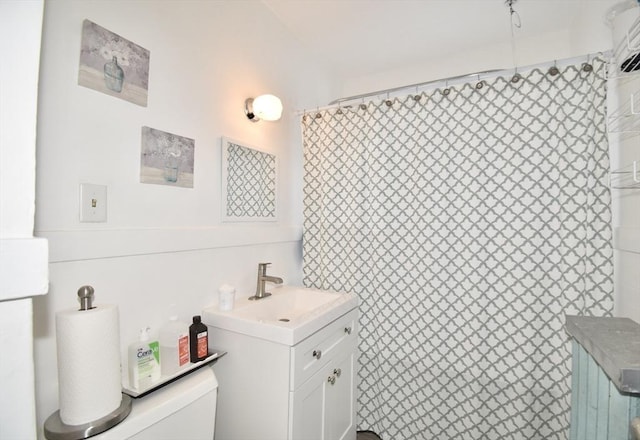 bathroom featuring toilet, vanity, and a shower with shower curtain