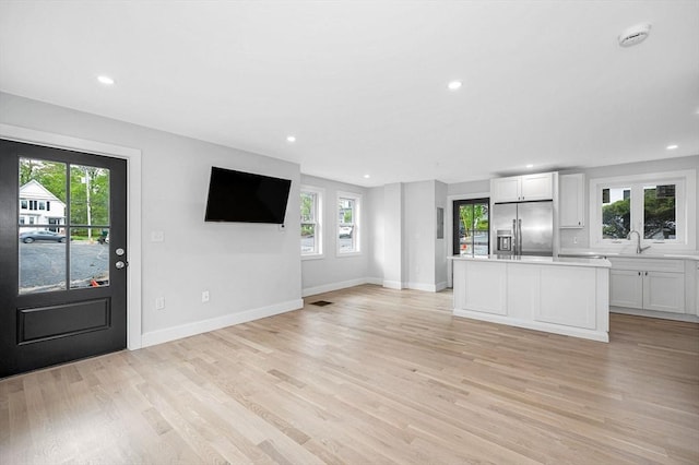 kitchen with stainless steel fridge with ice dispenser, white cabinetry, light wood-style flooring, plenty of natural light, and recessed lighting