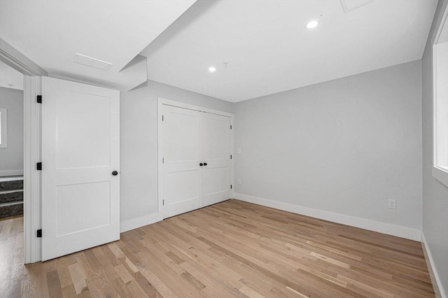 unfurnished bedroom featuring light wood-style floors, baseboards, recessed lighting, and a closet