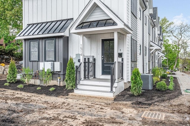 doorway to property featuring a standing seam roof, metal roof, central air condition unit, and board and batten siding