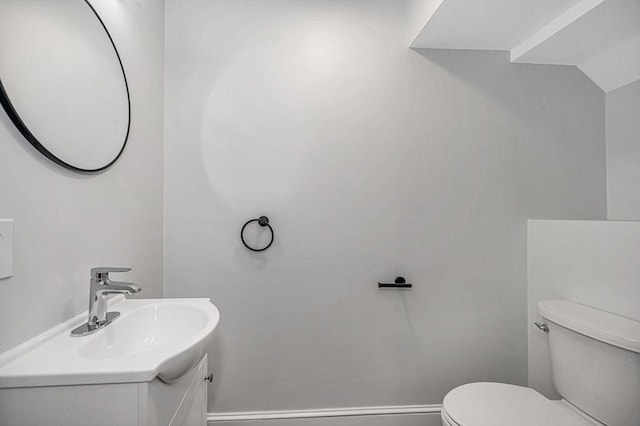 bathroom with toilet, vanity, and baseboards