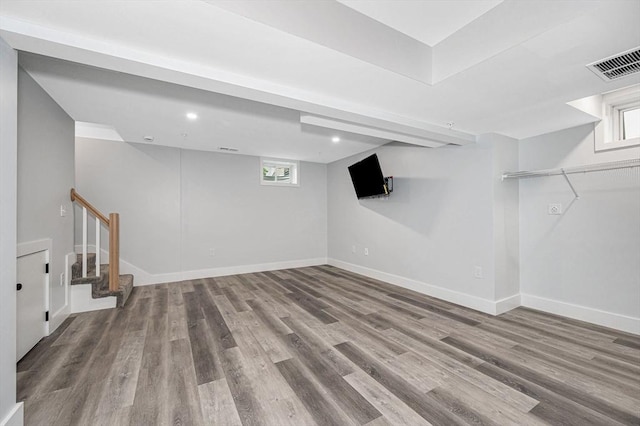 below grade area with wood finished floors, stairway, baseboards, and healthy amount of natural light