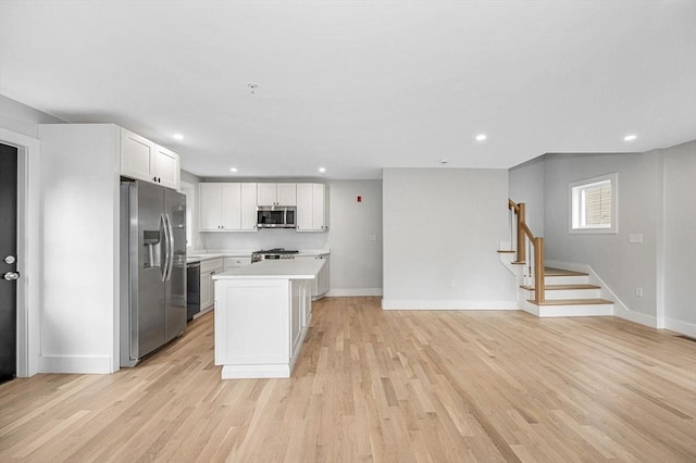 kitchen featuring appliances with stainless steel finishes, light countertops, white cabinetry, baseboards, and a center island