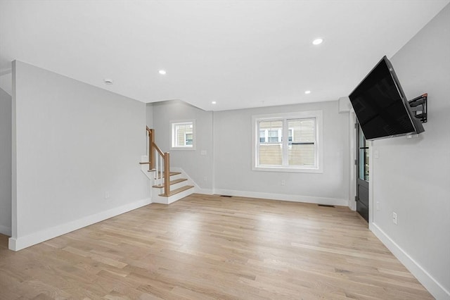 unfurnished living room with stairs, light wood-style flooring, baseboards, and recessed lighting
