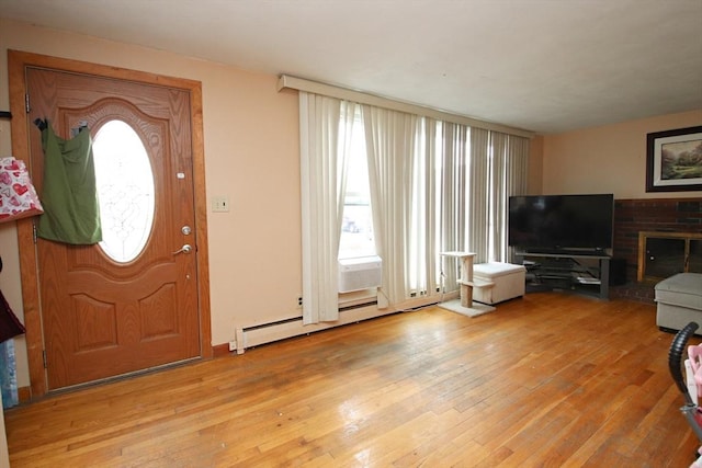 foyer entrance featuring a baseboard heating unit and light wood-type flooring