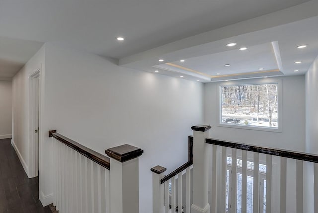 stairway featuring wood-type flooring and a raised ceiling